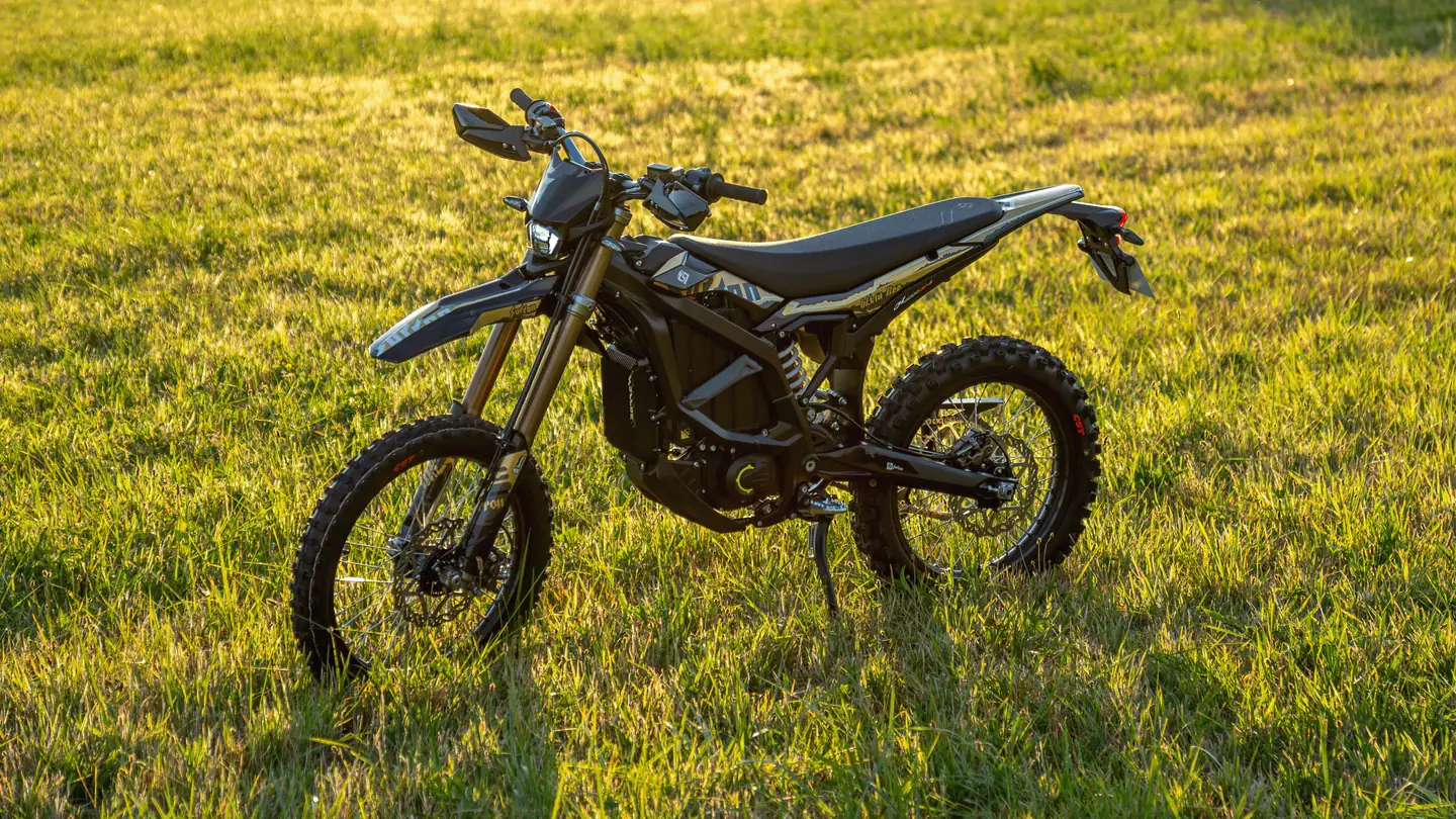 Sur-Ron Ultra Bee in voller Seitenansicht auf einer Sommerwiese